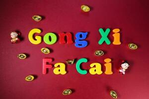 Plastik Alphabet Zeichen Beschriftung Gong xi Fa cai Chinesisch Neu Jahr auf kastanienbraun rot Papier Hintergrund Ornamente Barren foto