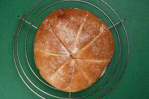 frisch gebacken Brot Laib runden auf Metall Grill Über Grün Hintergrund foto