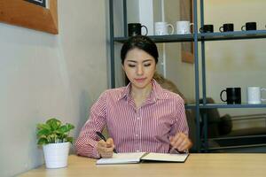 jung Süd Osten asiatisch Frau Geschäft Büro beim Cafe Stuhl Tabelle Arbeit Studie lesen foto