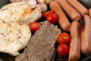 mischen Treffen schwenken Hähnchen Brust Rindfleisch Steak Würstchen Tomate Zwiebel Knoblauch Öl braten Grill auf Metall braten schwenken zwei hölzern Griff auf Weiß Hintergrund foto