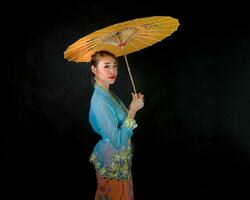asiatisch Frau im Zugkraft Kebaya Tragen Regenschirm auf schwarz Hintergrund foto
