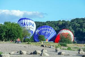 drei Blau und rot Luft Luftballons auf Rasen zwischen Grün Bäume Lügen Vor Sein völlig aufgeblasen unter Blau Himmel auf sonnig Tag foto