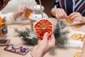 Frauenhand, die eine Dekoration aus getrockneter Grapefruit hält foto