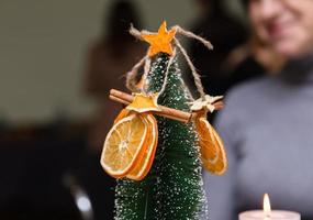 getrocknete orange Sterne von Mandarinen- und Zimtdekoration, die an einem Weihnachtsbaum hängen