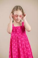 Porträt von ein süß wenig Mädchen im Rosa Kleid und Rosa Brille foto
