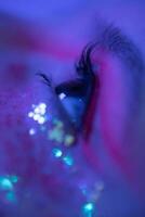 extrem Nahansicht von weiblich Auge mit glänzend bilden mit funkelt beleuchtet Pink Blau Neon- Licht foto