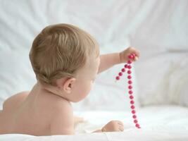 Baby auf Bett spielen mit Perlen foto