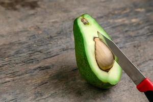 frische Avocado halbiert auf Holzbrett mit Messerhintergrund