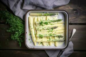 traditionell gedämpft Weiß Spargel mit Hollandaise Soße und Kräuter wie ein oben Aussicht im ein Emaille Tablett auf ein alt Holz Tabelle mit Kopieren Raum auf das Rechts, generieren ai foto