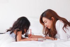 asiatische Mutter unterrichtet ihre Tochter Hausaufgaben zu Hause im Urlaub foto