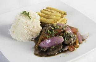 peruanisches Essen Lomo Saltado ein gesalzenes Rindfleisch mit Tomaten Zwiebel Bratkartoffeln und Reis foto