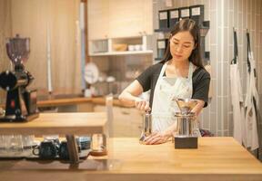 weiblich Hand Maische Kaffee Bohne im Kaffee Schleifer auf hölzern Tisch. foto