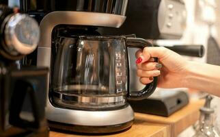 weiblich Hand verwenden ein Kaffee Maschine zum Kochen das Kaffee und vorbereiten Dienen zu ihr Kunde. foto