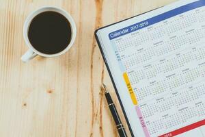 Kalender Planer mit Brunnen Stift und heiß Kaffee auf Holz Tisch.Büro Werkzeug. foto