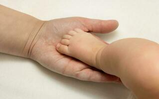 Babys Bein im Mutter Hand, Mutterschaft Konzept foto