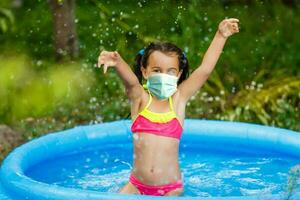 wenig Mädchen im ein schützend Maske verbringt Sommer- Ferien foto