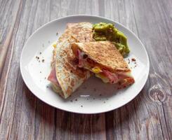 ein Teller von Essen mit ein Quesadilla und Guacamole auf Es. foto