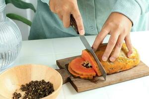 Hände halten ein Messer Schneiden Über reif Papaya foto