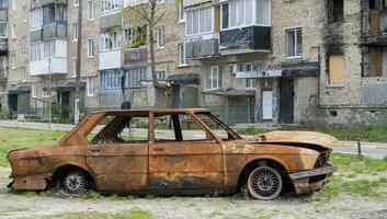 Konsequenzen von das Bombardierung im das Stadt. das Rakete blies oben das Haus. ein ausgebombt Wohnung Gebäude und ausgebrannt Autos nach ein Luftangriff. Löcher im das Wände von Muscheln. Überreste von Eigentum. foto