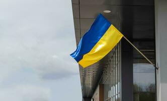 das National Flagge von Ukraine flattert im das Wind auf ein Fahnenstange, auf ein Gebäude. Blau und Gelb Farben auf das ukrainisch Flagge. Flagge von Ukraine auf das Fassade von das Regierung Gebäude. foto