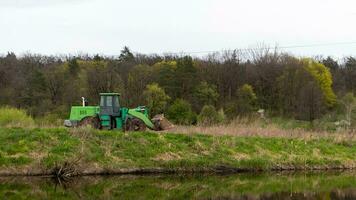 das Traktor Fahrten entlang das Bank von ein Fluss oder See im das Wald. foto