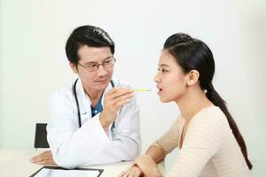 jung asiatisch männlich Arzt tragen Schürze Uniform Stethoskop weiblich geduldig sich unterhalten diskutieren Wange foto