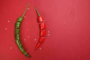 Grün rot Chili Pfeffer auf rot Papier Hintergrund Schnitt Stücke Saat foto