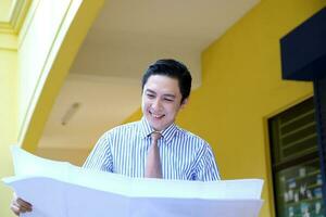 Süd Osten asiatisch jung malaiisch Chinesisch Mann tragen formal Krawatte suchen beim Entwurf beim draussen Konstruktion Seite? ˅ foto