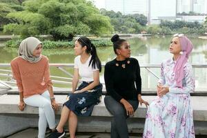 Gruppe von Frau malaiisch Chinesisch indisch malaysisch Treffen und grüßen Plaudern sich unterhalten zu jeder andere draussen Grün Park See Natur foto