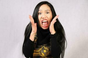 jung attraktiv Süd-Ost asiatisch Frau posieren Gesichts- Ausdruck Hand auf Wange überrascht schockiert erschrocken foto