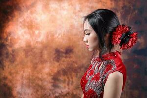 Süd Osten asiatisch Chinesisch Rennen ethnisch Ursprung Frau tragen rot Samt cheongsam mit Hand genäht Reihenfolge Arbeit Kleid Kostüm Hand Ventilator auf retro Jahrgang Hintergrund foto