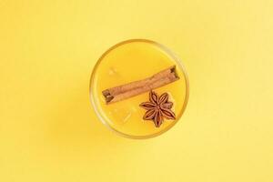 frisch Orange Zimt Star Anis Nelke würzen Saft im Glas auf Weiß Gelb Hintergrund foto