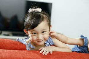 wenig Mädchen Kind suchen Über das Sofa lächelnd foto
