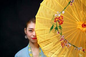 asiatisch Frau im Zugkraft Kebaya hinter Regenschirm auf schwarz Hintergrund foto