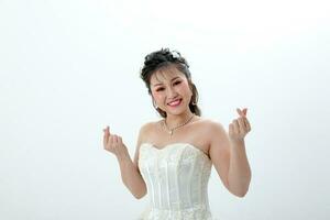 jung asiatisch Frau im Weiß Kleid Haar erledigt mit Krone auf Weiß Hintergrund Liebe Finger Zeichen foto