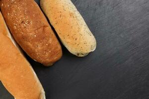 frisch gebacken Brot Laib Brötchen rollen runden lange mischen Wahrheit Kopieren Text Raum Rand Rahmen schwarz Hintergrund foto