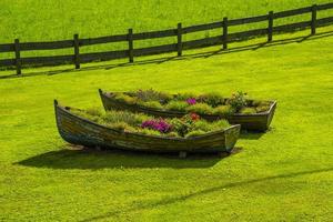 Zwei alte Holzboote als Pflanzgefäße inmitten eines grünen Rasens