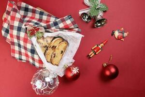 Weihnachten Weihnachten Dekoration Ornament Glocke Geschenk überprüft Stoff Stoff wickeln geschnitten Stollen Obst Kuchen Essen Kiefer Obst auf rot Hintergrund foto