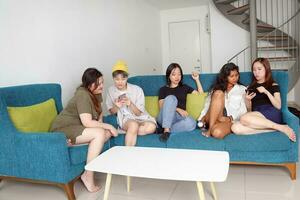 jung asiatisch Frau Gruppe sich unterhalten Klatsch Plaudern singen Party Spaß genießen Emotion auf Blau Leben Zimmer Sofa foto