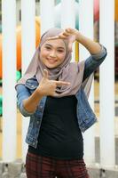 jung asiatisch malaiisch Muslim Frau Kopftuch draussen Grün Pose Hand Finger Rahmen Gesicht foto