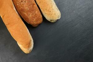 frisch gebacken Brot Laib Brötchen rollen runden lange mischen Wahrheit Kopieren Text Raum Rand Rahmen schwarz Hintergrund foto