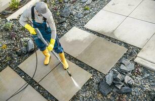 Hausbesitzer Waschen aus Schmutz von seine Garten Beton Wege mit Druck Unterlegscheibe foto