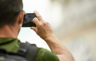 Männer mit Rucksack nehmen Bilder mit seine Smartphone foto