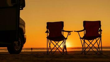 Strand Sonnenuntergang Aussicht mit rv Wohnmobil und Camping Stühle foto