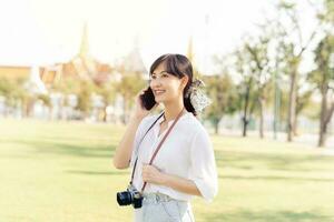 Porträt schön jung asiatisch Frau mit Smartphone auf Sommer- Urlaub Ferien Ausflug mit das großartig Palast im ein Hintergrund beim Bangkok, Thailand foto