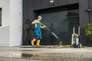 Männer Druck Waschen seine Garage Tor foto