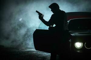 nachdenklich Gangster spielen mit seine Pistole während spät Nacht foto