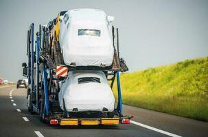 Auto Träger Anhänger voll von Fahrzeuge Fahren Nieder das Autobahn foto