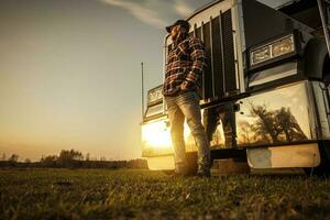 Trucker im Vorderseite von seine halb LKW während Sonnenuntergang foto