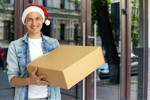 Mann im Santa Hut mit ein groß Geschenk, Weihnachten Lieferung foto